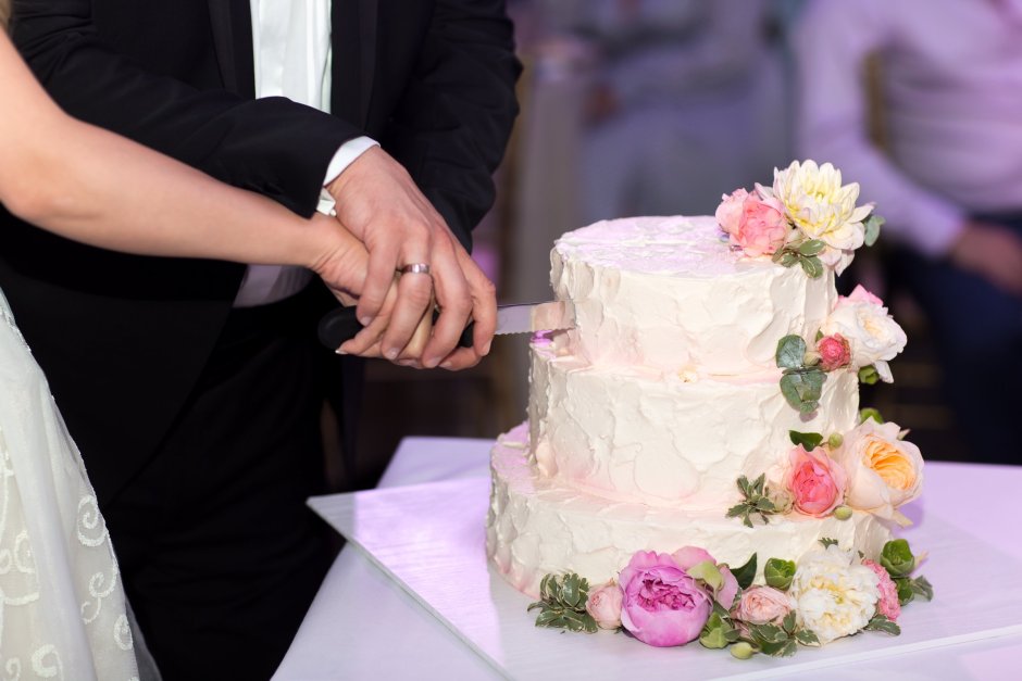 Молодожены разрезают свадебный торт