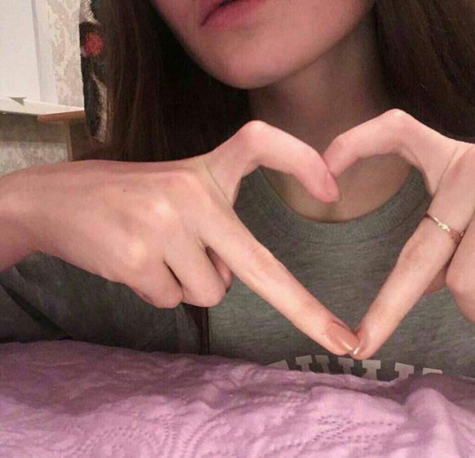 Девушка показывает сердечко пальцами