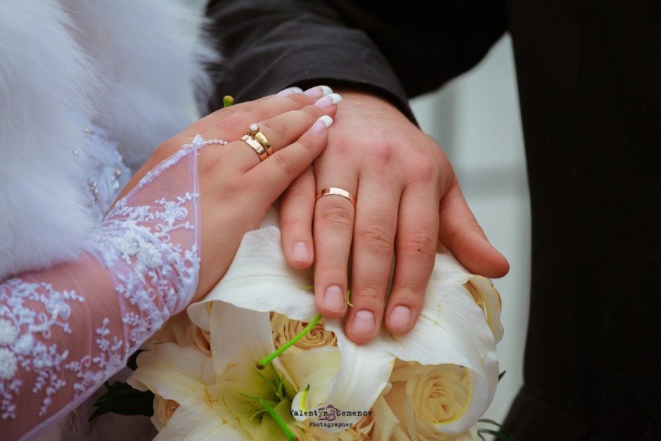 Обручальные кольца на пальцах жениха и невесты